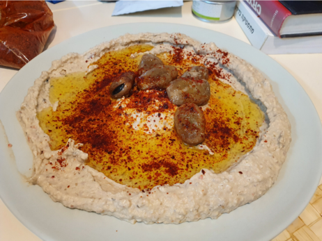 Foul Mudammas on a plate with olive oil, paprika and whole beans for garnishing