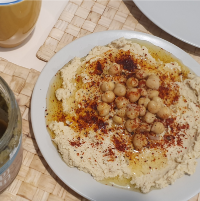humus served on a plate with olive, paprika, and chickpeas on top