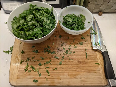 A soup bowl and a small prep bowl full of roughly chopped cilantro.