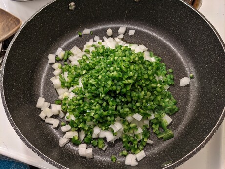 Peppers and onions in a large frying pan.